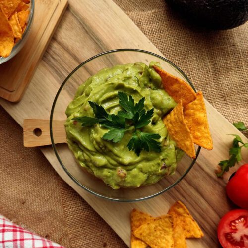 Guacamole in a bowl with tortilla chips on the side